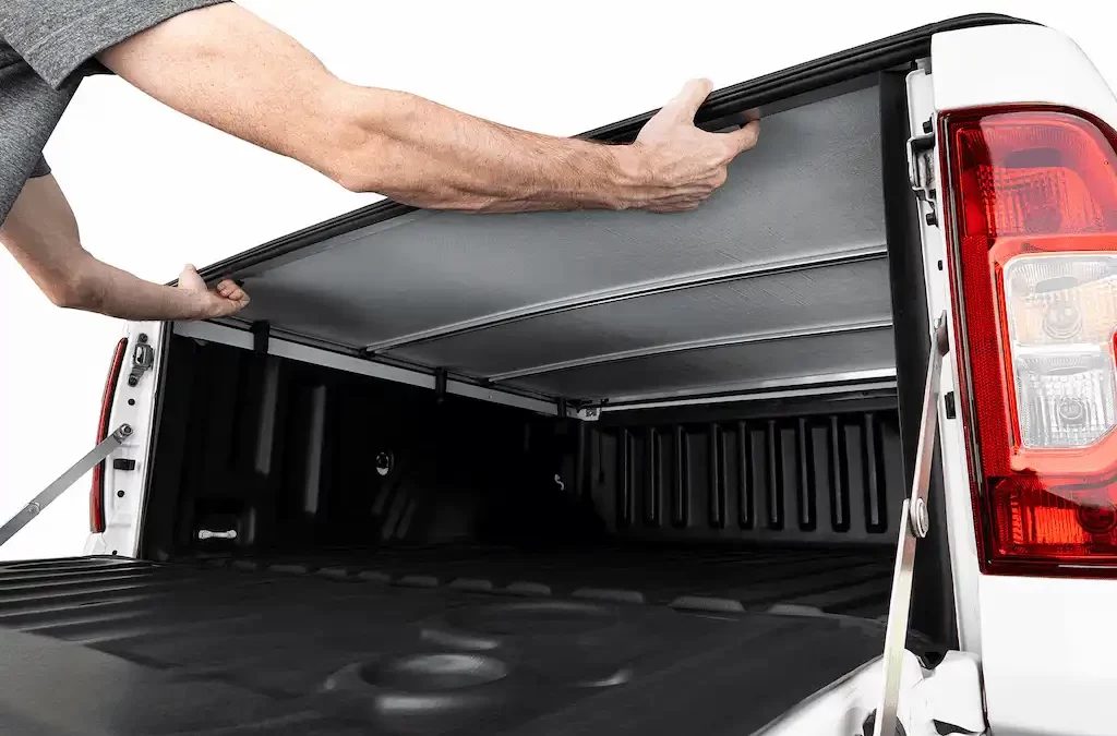 Pessoa manuseia capota em caminhonete destacando funcionalidade e proteção do acessório. A imagem ilustra características que consumidores buscam ao escolher a melhor capota marítima Fiat Toro.